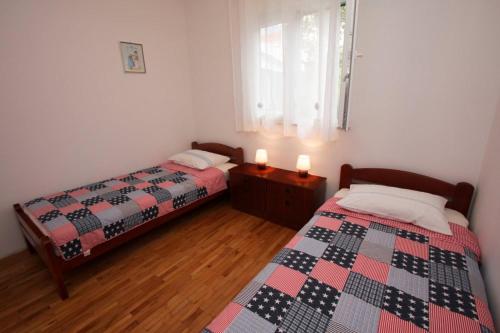 a bedroom with two beds and two candles on a table at Apartment Miljenko Tomić in Splitska