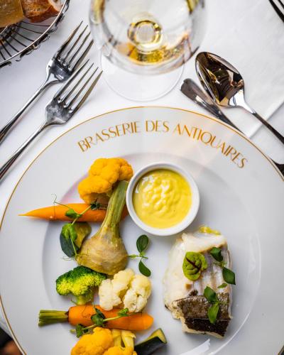 a plate of food with vegetables and a bowl of sauce at Hôtel La Cour du 6 in Annecy