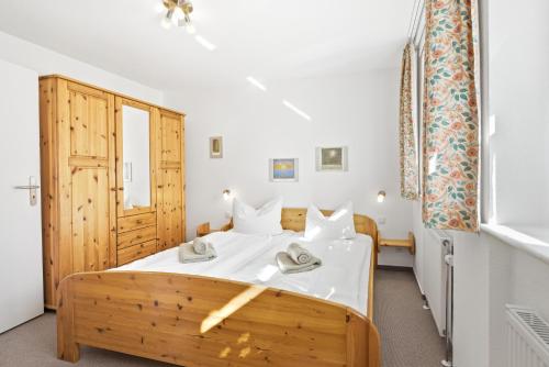 a bedroom with a wooden bed and a window at Achtern Diek 13a - Wohnung 2 in Müggenburg