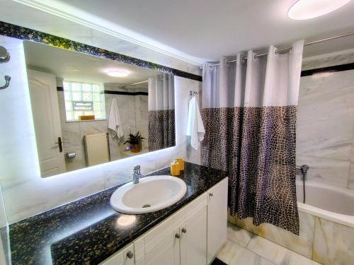 a bathroom with a sink and a mirror and a tub at Christina's Cottage in Agios Nikolaos