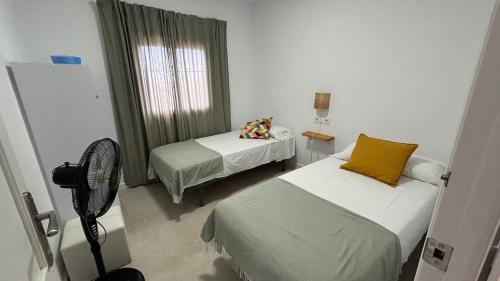 a room with two beds and a fan at Finca La Arboleda in Chipiona