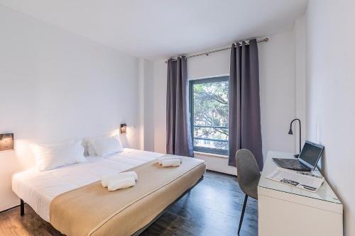 a bedroom with a bed and a desk with a laptop at HI Lisboa Oriente - Pousada de Juventude in Lisbon
