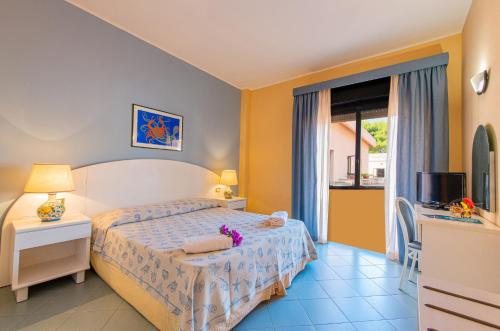a bedroom with a bed and a tv and a window at VOI Florio Resort in Cinisi