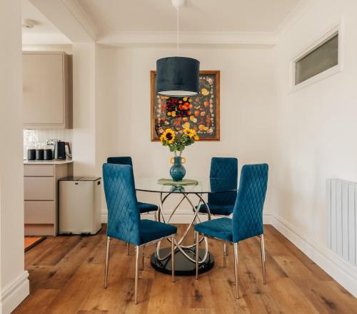 a dining room with blue chairs and a glass table at Family apartment with balcony 2 min walk to Hyde Park in London