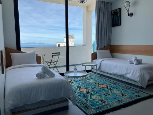 a bedroom with two beds and a table and a window at YaYaCaSa in Tangier