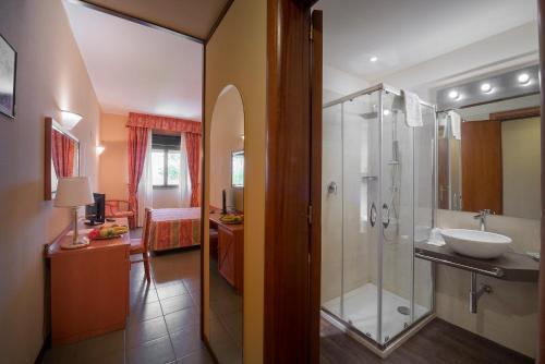 a bathroom with a glass shower and a sink at VOI Florio Resort in Cinisi