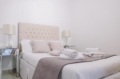 a white bedroom with a large bed with towels on it at Studio Apartment By Travel Lets Holiday Homes Lagada With Pool in Makry Gialos