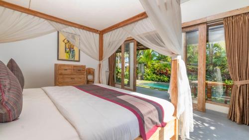 a bedroom with a bed and a large window at Diva Villa Sanggingan Ubud in Ubud