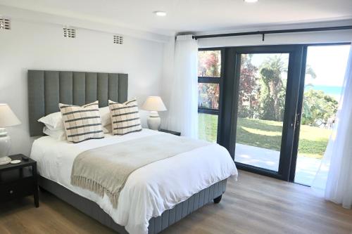 a bedroom with a large bed and a large window at Chintsa Oceanfront in Chintsa