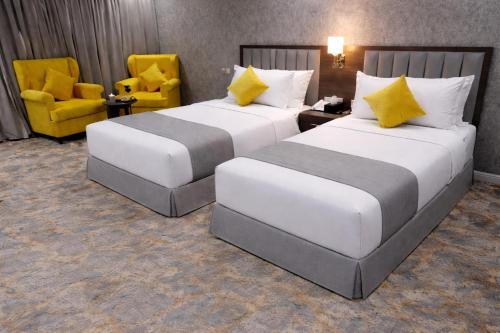 zwei Betten in einem Hotelzimmer mit gelben Stühlen in der Unterkunft WS Hotel in Tabuk
