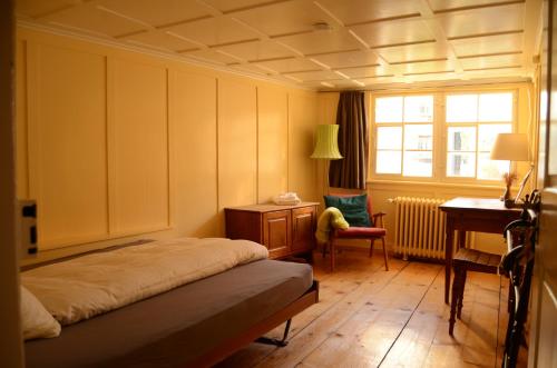a bedroom with a bed and a desk and a window at Gasthaus Rössli in Trogen