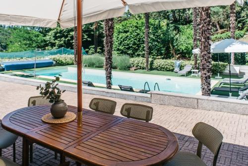 a wooden table and chairs with an umbrella and a pool at Villa Pegasus in Turin