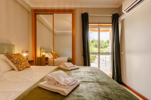 a bedroom with a bed with two towels on it at Caldas Charm Getaway - Garden Terrace & Comfort in Caldas da Rainha