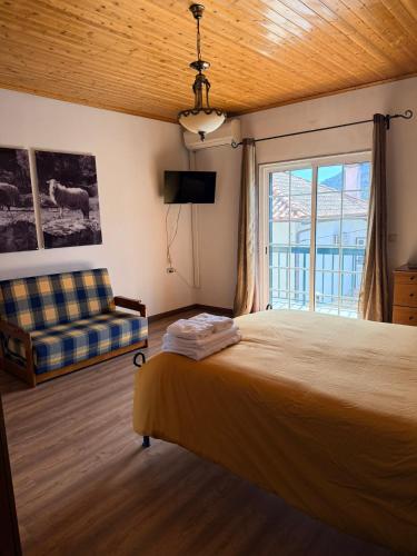 a bedroom with a bed and a couch and a window at Casa de São Luís - Turismo Rural in Torre de Moncorvo