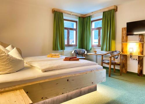 a bedroom with a bed with green curtains and a desk at Pension Zum Talwächter im Sandsteinidyll in Rathen