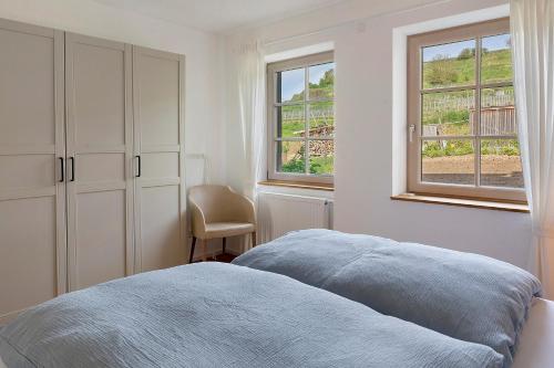 a white bedroom with a bed and two windows at Feierabend am Kaiserstuhl in Bötzingen