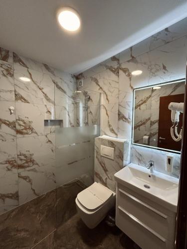 ein Badezimmer mit Toilette, Waschbecken und Spiegel in der Unterkunft Hotel Bristol in Mostar