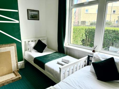 a small room with two beds and a window at Chic victorian 1 bed flat - sleeps 4 - free parking - pet friendly in Bradford