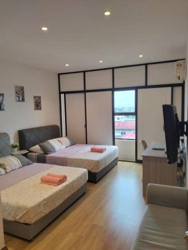 a bedroom with two beds and a flat screen tv at Roxy Apartment Kuching in Kuching