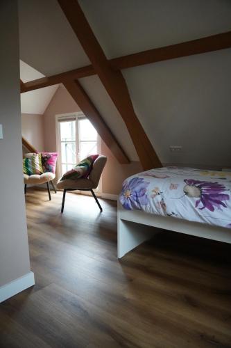 a bedroom with a bed and a chair in a attic at Natuurhuisje Laanzicht Ophemert in Ophemert