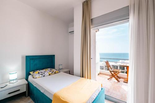 a bedroom with a bed and a balcony with the ocean at Saranda Blueriver apartment in Sarandë