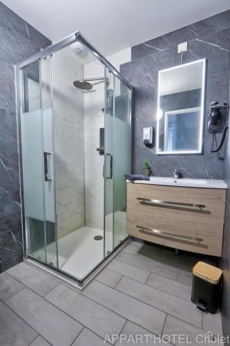 a bathroom with a glass shower and a sink at Appart' hôtel Cholet in Cholet