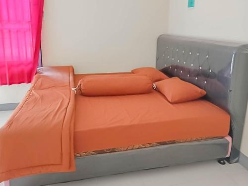 a bed with orange pillows on it in a room at Verisha Inn Singkawang RedPartner in Singkawang