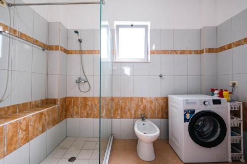 a bathroom with a washing machine and a toilet at Saranda Blueriver apartment in Sarandë