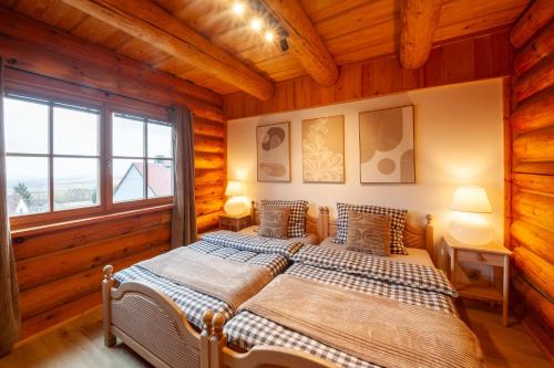 two beds in a room with wooden walls at Srub Chodov in Chodov