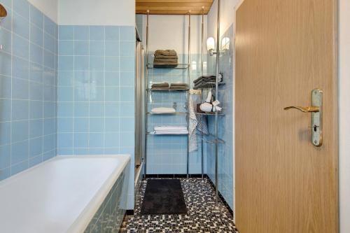 a bathroom with a tub and a shower with blue tiles at Traumhaftes Wohnen beim Badesee in Erlangen