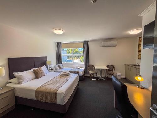 a hotel room with a bed and a table and chairs at Gracelands Parkes in Parkes