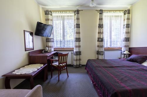 a bedroom with a bed and a desk with a computer at Pensjonat Pod Długą Polaną in Nowy Targ