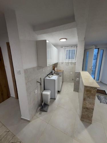 a large white kitchen with a sink and a toilet at Apartmani ,,Merlin,, in Utjeha