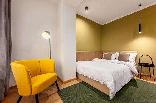 a bedroom with a bed and a yellow chair at Apartament Nordic 3 in Gura Humorului
