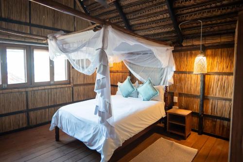 a bedroom with a bed with a mosquito net at Tofo Beach Gardens in Inhambane