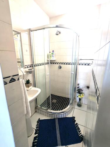 a bathroom with a shower and a blue rug at OceanFront- Whale Watch- On Beach- Stunning in Umdloti