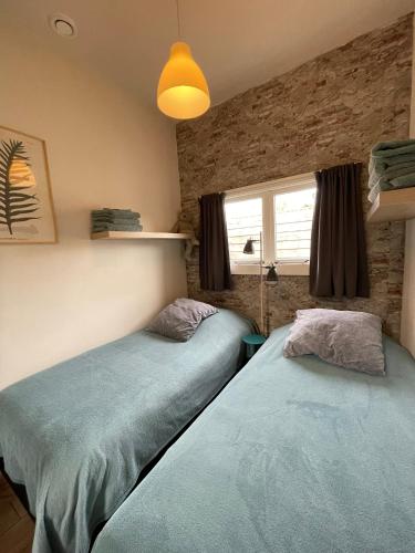 two twin beds in a room with a window at De Cel in Nes