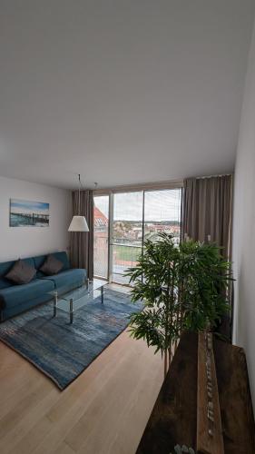 a living room with a blue couch and a large window at Speicher Barth - Superior-Hotel in Barth