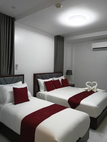 two beds in a hotel room with red pillows at KJSGrandeInn in Manolo Fortich