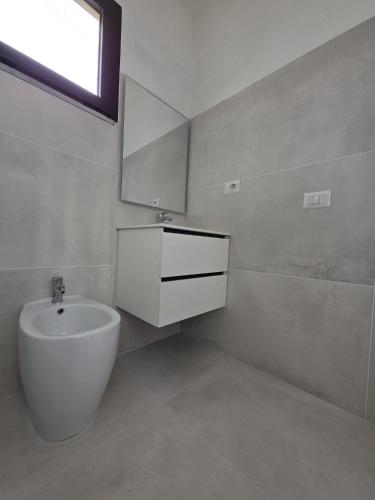 a white bathroom with a sink and a mirror at Casa Giulia in Stintino