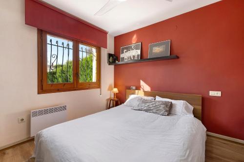 a bedroom with a white bed and a red wall at Casa Abril in L'Ampolla