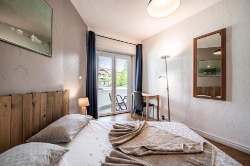 a bedroom with a bed and a mirror and a window at Appartement Proche Lac et Thermes in Thonon-les-Bains