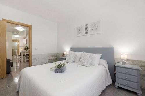a white bedroom with a white bed and a table at Apartament Cristina in Deltebre