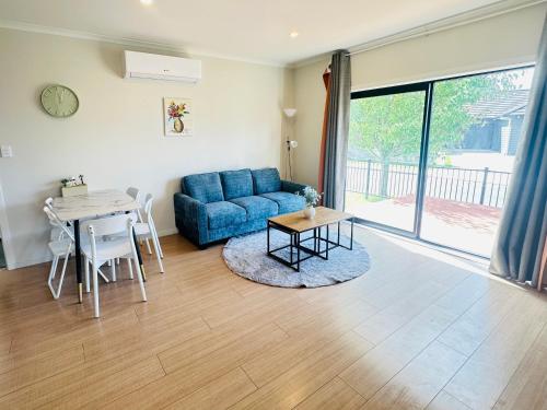 a living room with a blue couch and a table at Modern Comfy 3 Bedrooms House in Chartwell in Hamilton