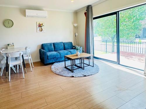 a living room with a blue couch and a table at Modern Comfy 3 Bedrooms House in Chartwell in Hamilton