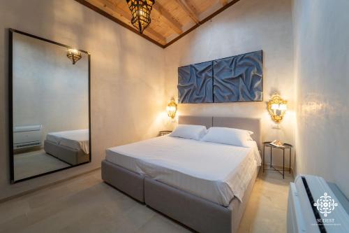 a bedroom with a large white bed and a mirror at Casa Philomena - Fascino storico in centro in Noto