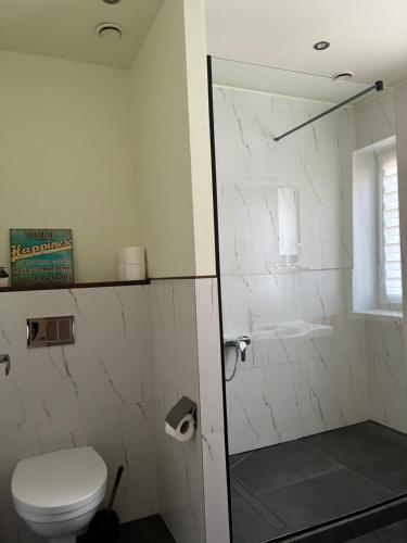 a white bathroom with a toilet and a shower at Vaivari Retreat in Jūrmala