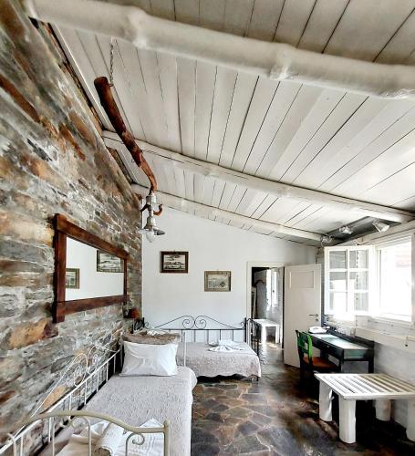 a room with two beds and a stone wall at Stone Kypri Apartment Andros in Kipri