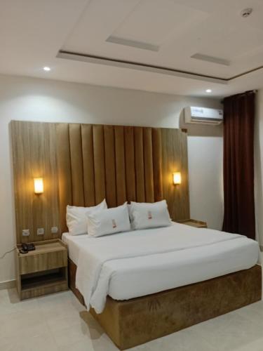 a bedroom with a large bed with a wooden headboard at Motion Hotel and Suites, Uyo in Uyo