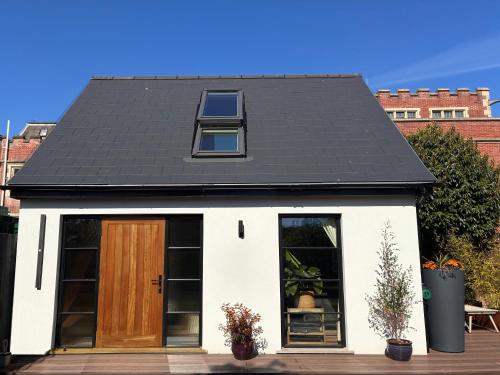 a small white house with a black roof at Hastings Casita, 'little house' self contained garden lodge, close to town and seafront in Hastings